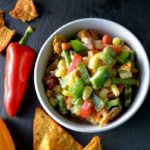 Nacho Corn Salad in a white bowl with red and yellow peppers from www.ApronFreeCooking.com