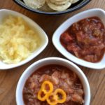 Pineapple Salsa with nacho chips, served in white bowls.