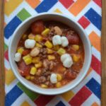 No Bean Chili in white bowl with mutli colored table cloth. Easy to make chili from www.ApronFreeCooking.com