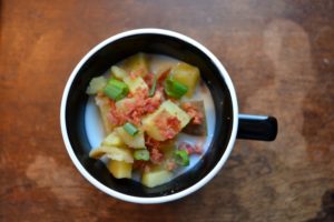 Potato soup in black mug on wooden table from www.ApronFreeCooking.com