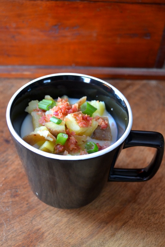 Potato soup in black mug on wooden table from www.ApronFreeCooking.com