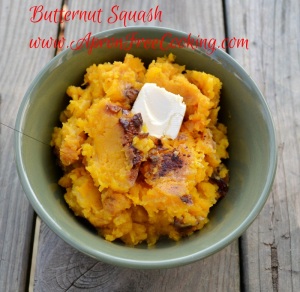 Mashed orange Butternut Squash topped with pat of butter and brown sugar in a green bowl. 