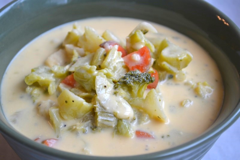 Close up of Broccoli Cheese soup in green bowl showing carrots and celery from www.ApronFreeCooking.com