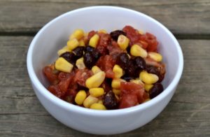 Simple Corn Salad in a white bowl made with black beans and red tomatoes from www.ApronFreeCooking.com
