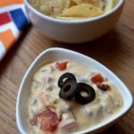 Simple Queso Dip with nacho chips in a white bowl from www.ApronFreeCooking.com
