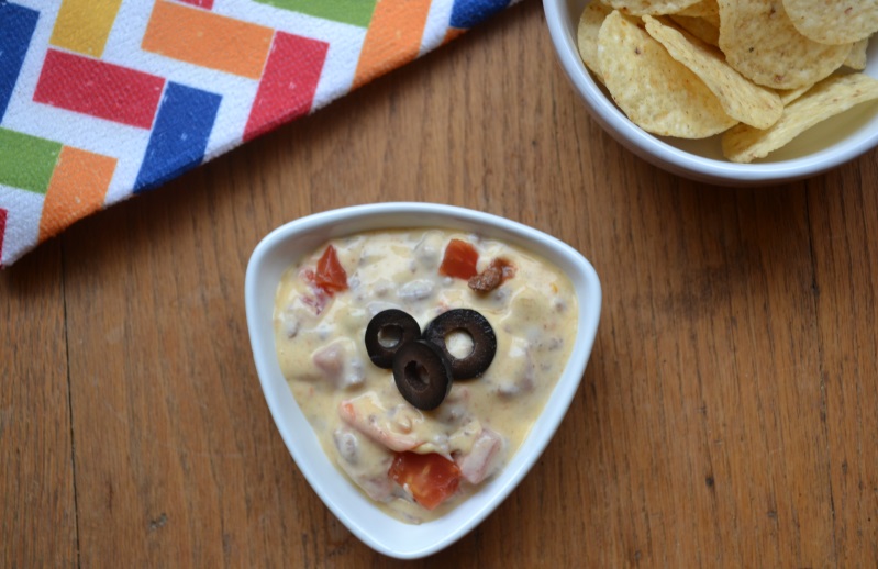 Simple Queso Dip with nacho chips in a white bowl from www.ApronFreeCooking.com