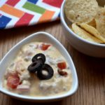Simple Queso Dip with nacho chips in a white bowl from www.ApronFreeCooking.com