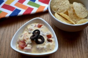 Simple Queso Dip with nacho chips in a white bowl from www.ApronFreeCooking.com