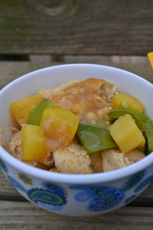 Pineapple Smothered Chicken with green peppers in white bowl with brown rice and sauce from www.ApronFreeCooking.com