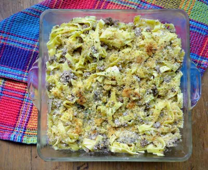 Grandma's Noodle Casserole in clear glass pan on blue purple and yellow cloth from www.ApronFreeCooking.com
