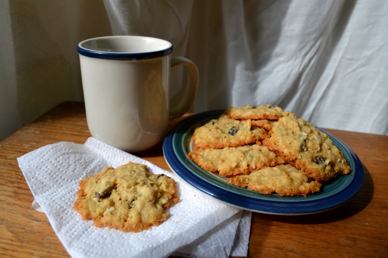 A plate of Coconut Raisin Mason Jar Cookies sit beside a cup of coffee from www.ApronFreeCooking.com