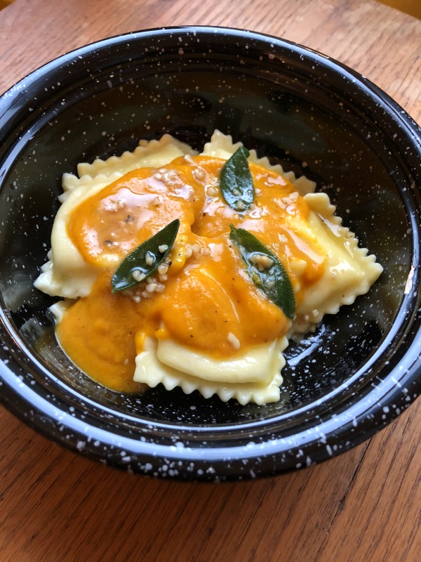 Pumpkin sauce with sage leaves in brown butter over cheese ravioli served in a black bowl from www.ApronFreeCooking.com