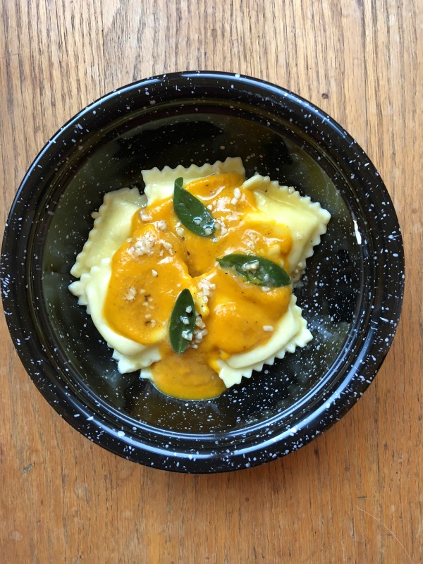 Pumpkin sauce with sage leaves in brown butter over cheese ravioli served in a black bowl from www.ApronFreeCooking.com