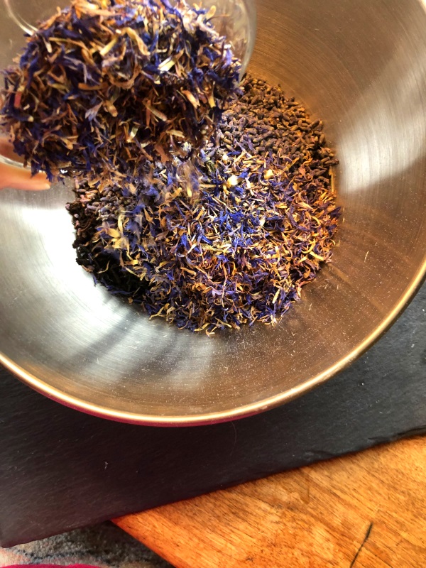 Blue cornflower petals being added to bowl with Earl Gray tea to make Blue Moon tea from www.ApronFreeCooking.com