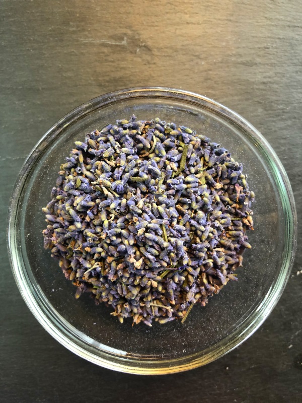 Glass bowl of light purple lavender flower buds on gray background from www.ApronFreeCooking.com