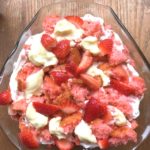 Strawberry trifle pictured from above, whipped cream topped with bits of cake and slices of strawberries from www.ApronFreeCooking.com