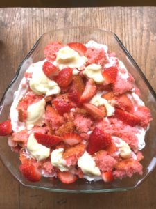Strawberry trifle pictured from above, whipped cream topped with bits of cake and slices of strawberries from www.ApronFreeCooking.com