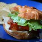 Deluxe BLT Sandwich served on blue plate with potato chips from www.ApronFreeCooking.com