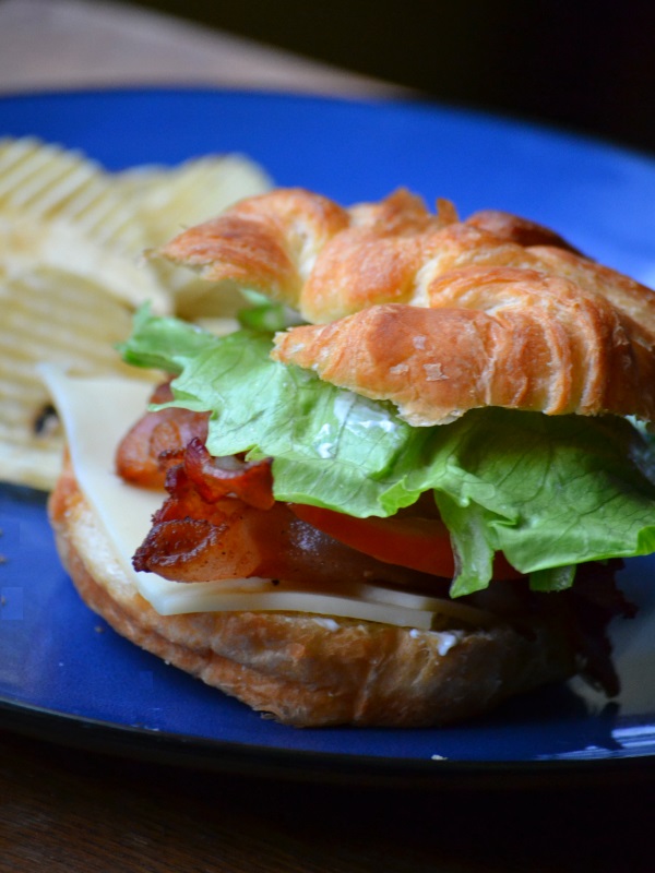 Deluxe BLT Sandwich served on blue plate with potato chips from www.ApronFreeCooking.com