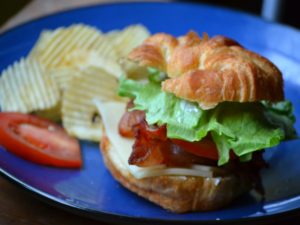 Deluxe BLT Sandwich served on blue plate with potato chips from www.ApronFreeCooking.com