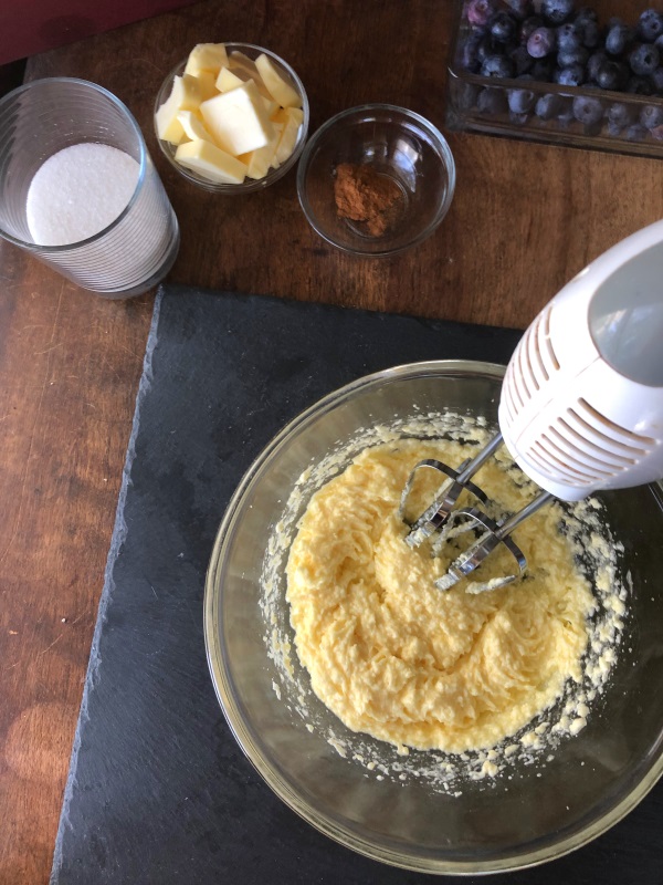Electric mixer beating egg, butter and sugar in glass mixing bowl