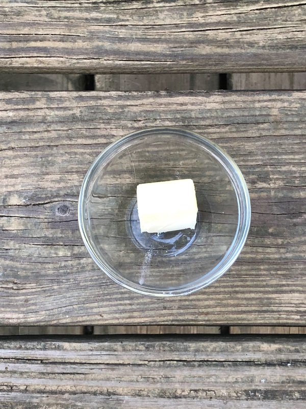 Blueberry Cornbread Muffin Ingredients Butter pat in clear glass bowl on wooden background.