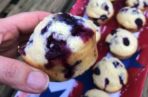 Blueberry Cornbread Muffins on a flag printed tray in background. Forefront is a blueberry cornbread muffin