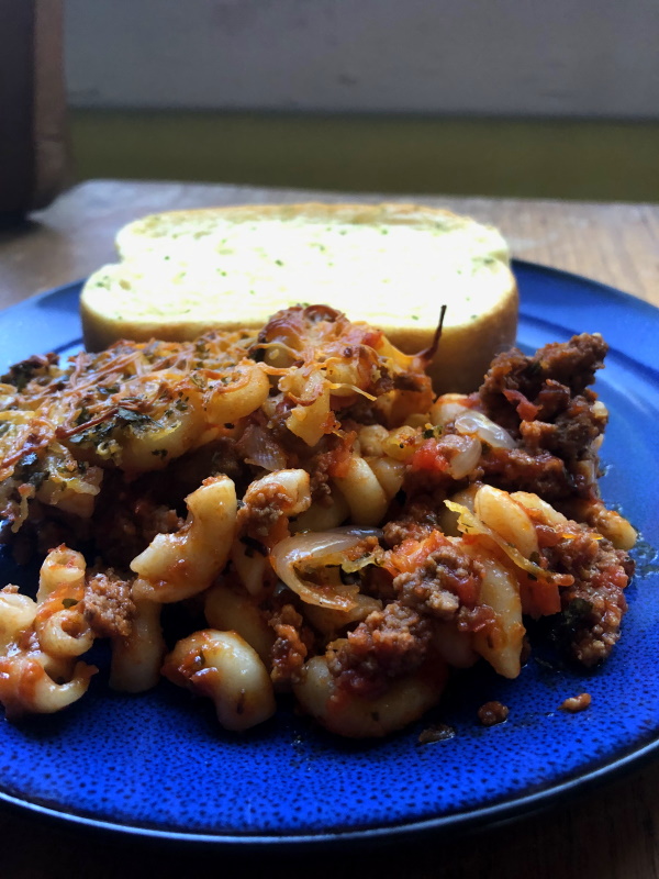 Serving of Johnny Marzetti on blue plate with garlic bread