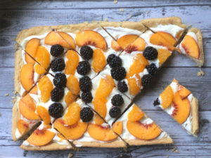 Peach Blackberry Fruit Pizza slices on gray wooden background