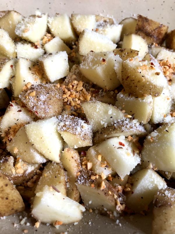 parmesan cheese and spices over potatoes for herb roasted potato recipe