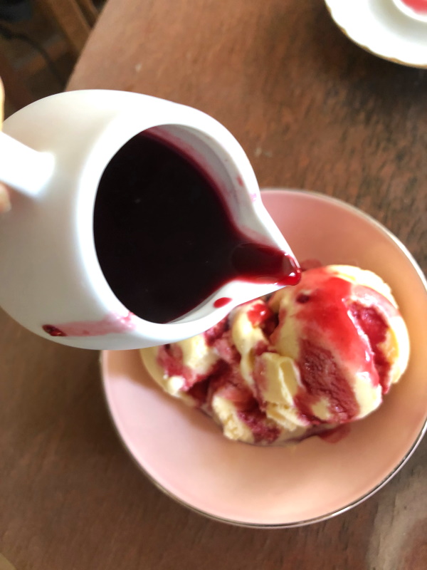 Raspberry syrup poured over vanilla ice cream