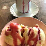 vanilla ice cream in pink bowl topped with homemade raspberry syrup